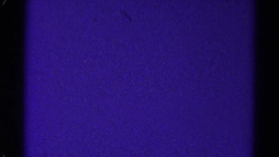 A lower contact-sheet frame showing a darker purple 8mm field, black border areas, grain, and faint marks from the 1967 Colorado reel.