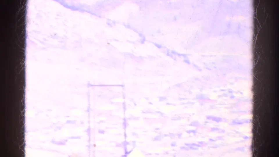 Overexposed 1967 Colorado 8mm frame where a distant valley scene and utility poles are faintly visible through bright film exposure.