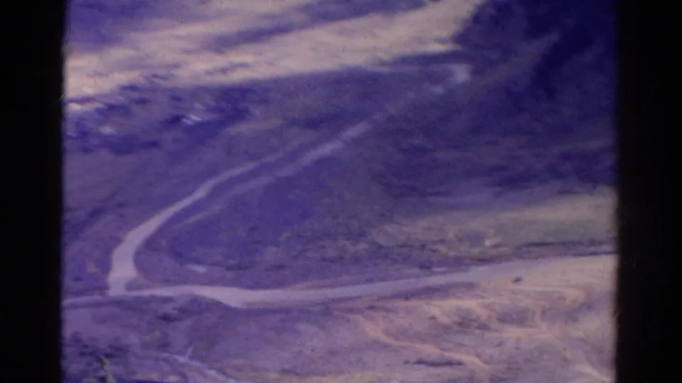 1967 Colorado 8mm aerial frame with soft focus, winding roads, dry land, and heavy faded purple color.