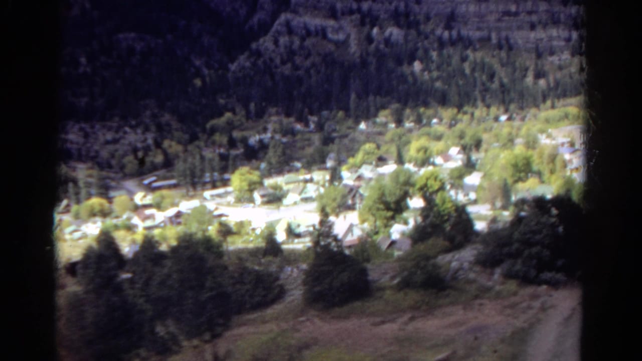 Mountain town in a valley seen through a dark foreground opening.