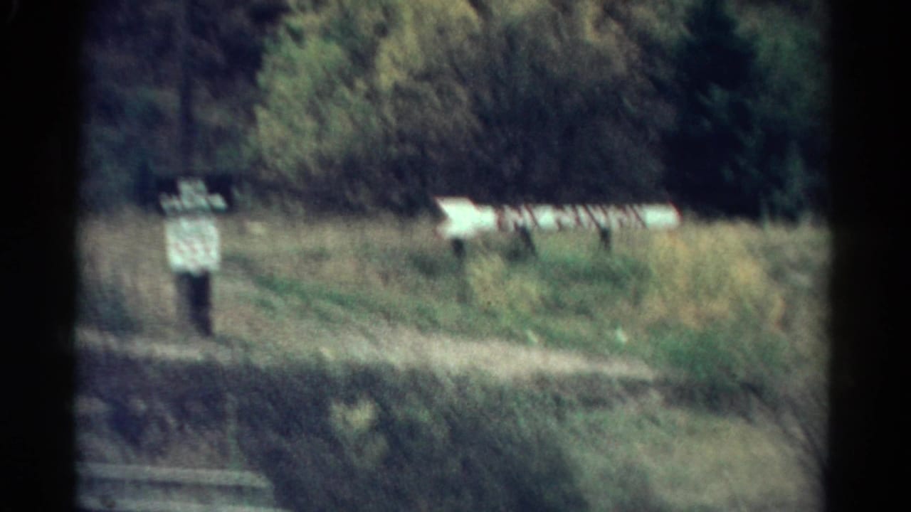 Distant roadside sign and arrow marker near a grassy path.