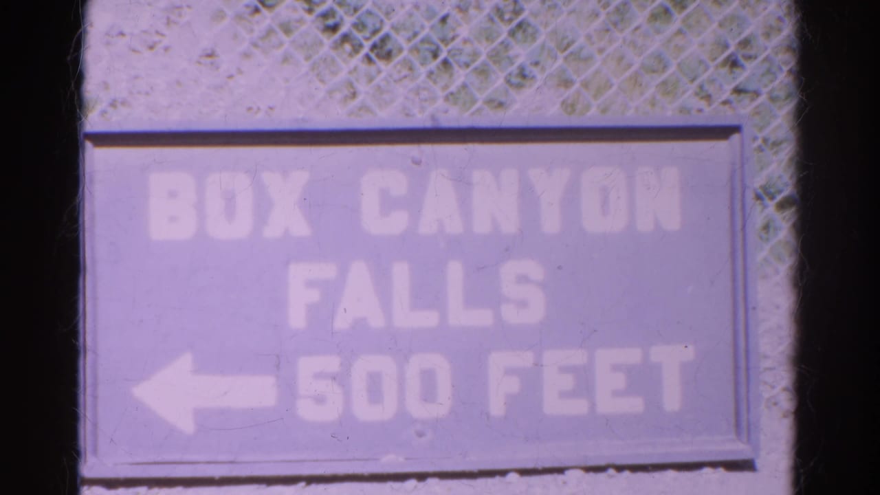 Weathered sign reading Box Canyon Falls 500 feet with a left arrow.