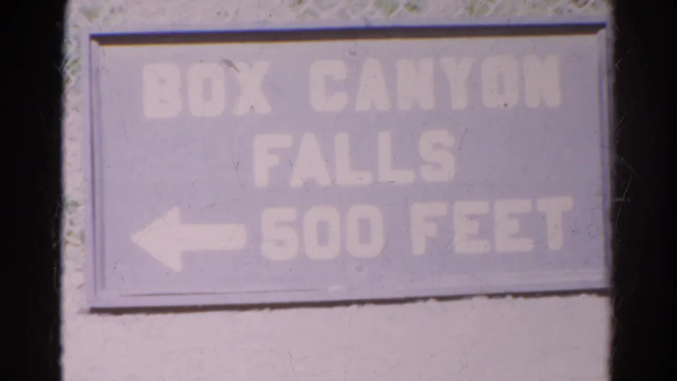 Close 8mm view of the Box Canyon Falls sign, with the distance lettering washed by exposure and film aging.