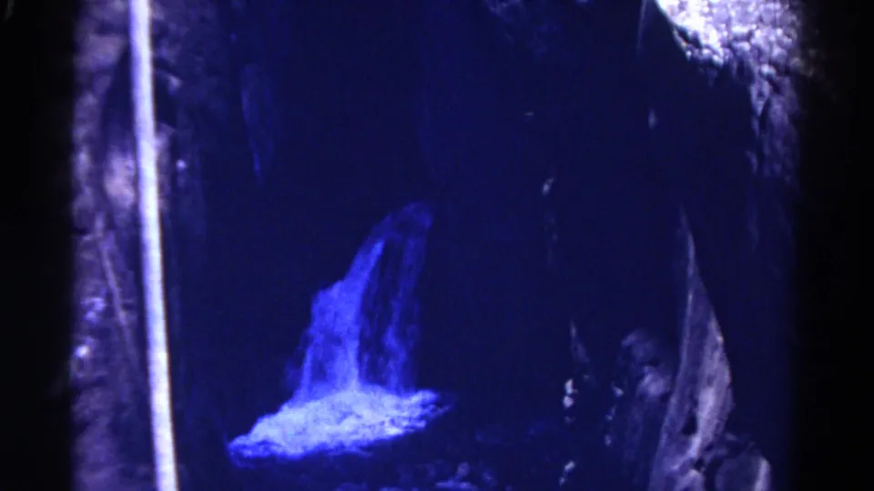 1967 Colorado 8mm view of a blue-toned waterfall and spray set against shadowed rock walls.