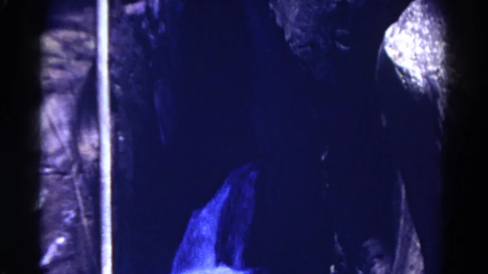 1967 Colorado 8mm frame showing blue-lit cave rock surfaces, dark recesses, and a bright vertical film or scene edge.