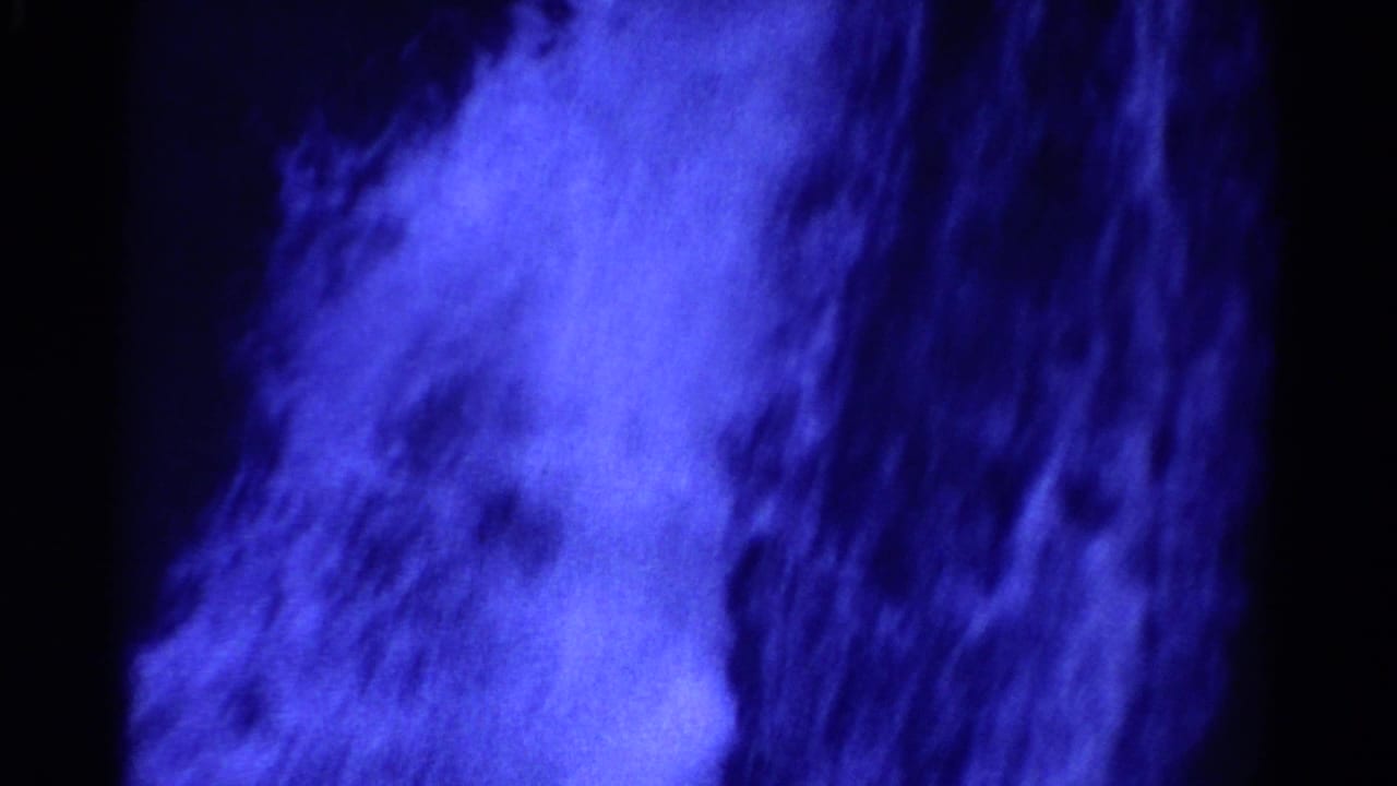 1967 Colorado 8mm frame with bright blue turbulent water or spray against a dark, high-contrast background.