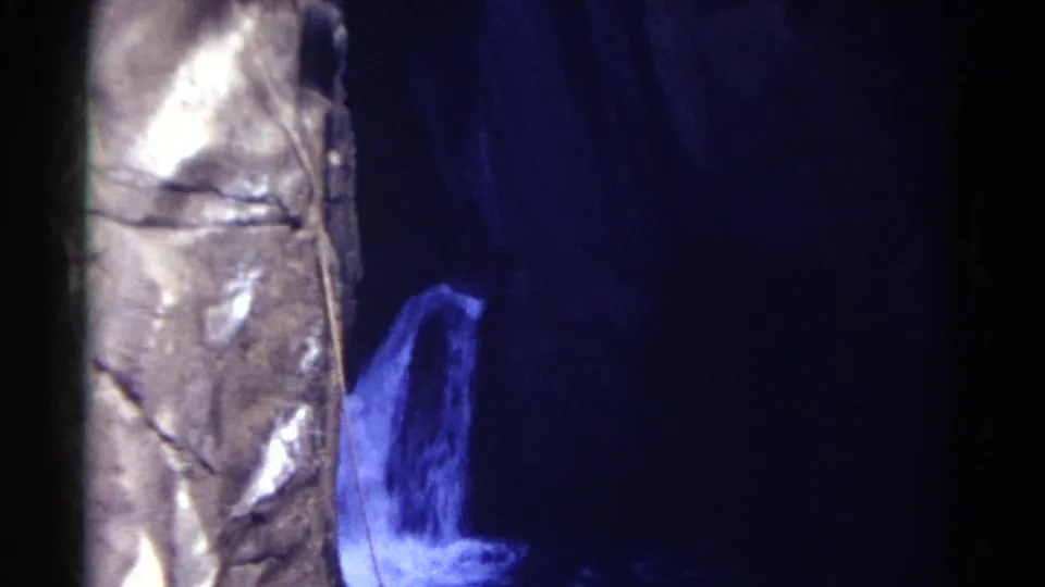 1967 Colorado 8mm frame with a pale textured vertical surface at left and dark blue water or spray at right.