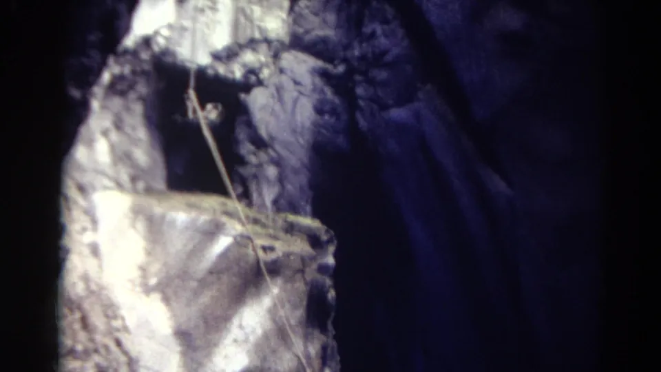 1967 Colorado 8mm frame with a close view of the textured metallic-looking structure, dangling rope, and blue-lit water or mist behind it.