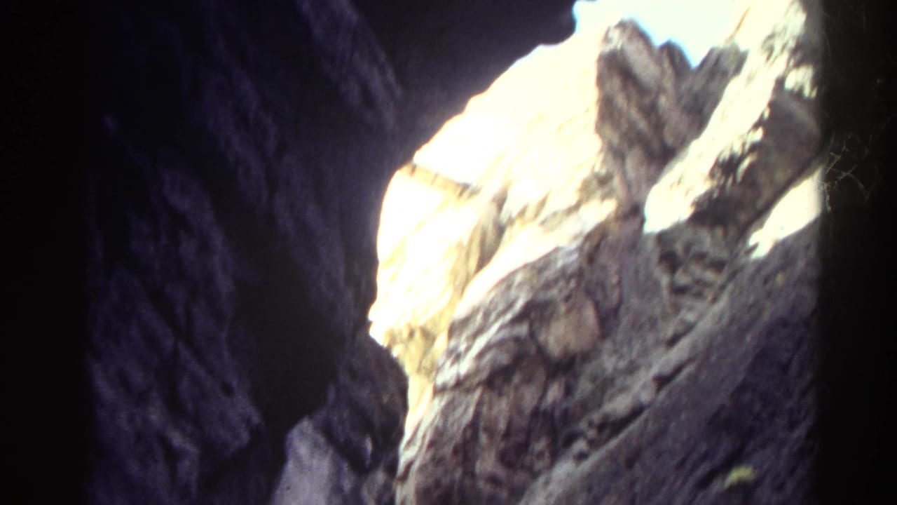 1967 Colorado 8mm frame looking from deep canyon shadow toward bright, sunlit rock walls.