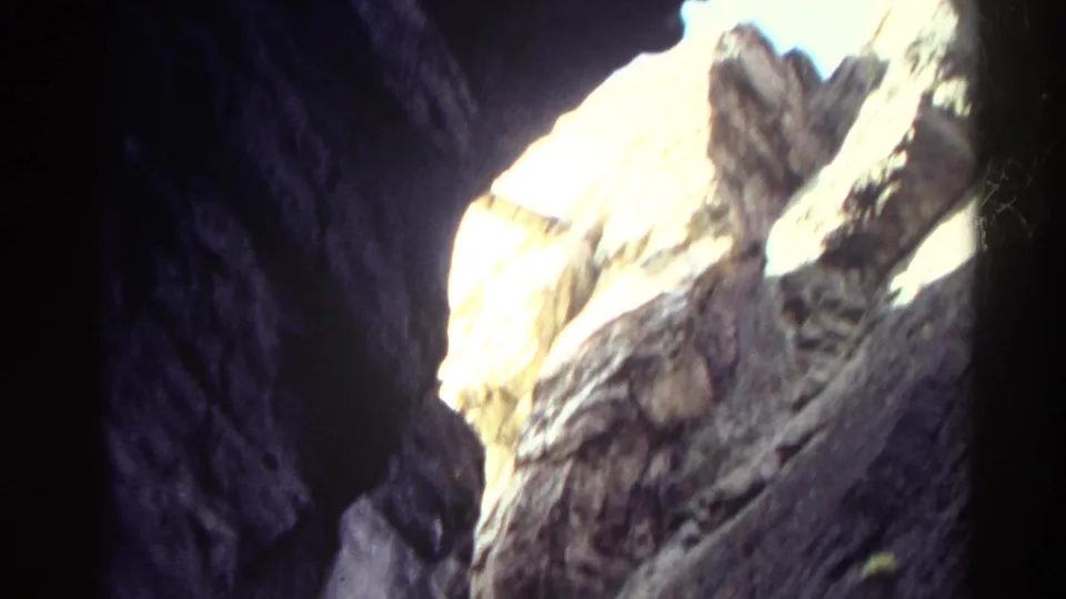 1967 Colorado 8mm frame looking from deep canyon shadow toward bright, sunlit rock walls.