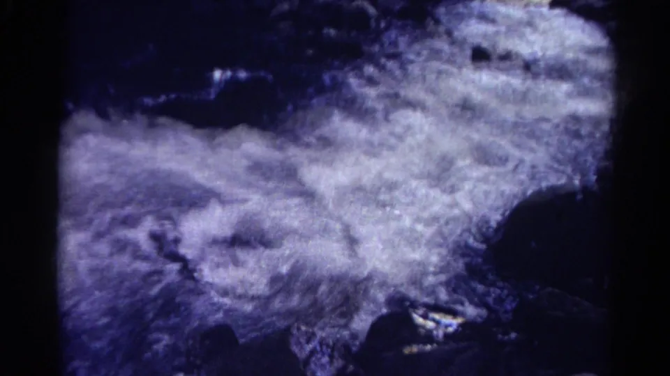 Soft 8mm Colorado canyon frame showing bright, foamy moving water between dark rock edges.