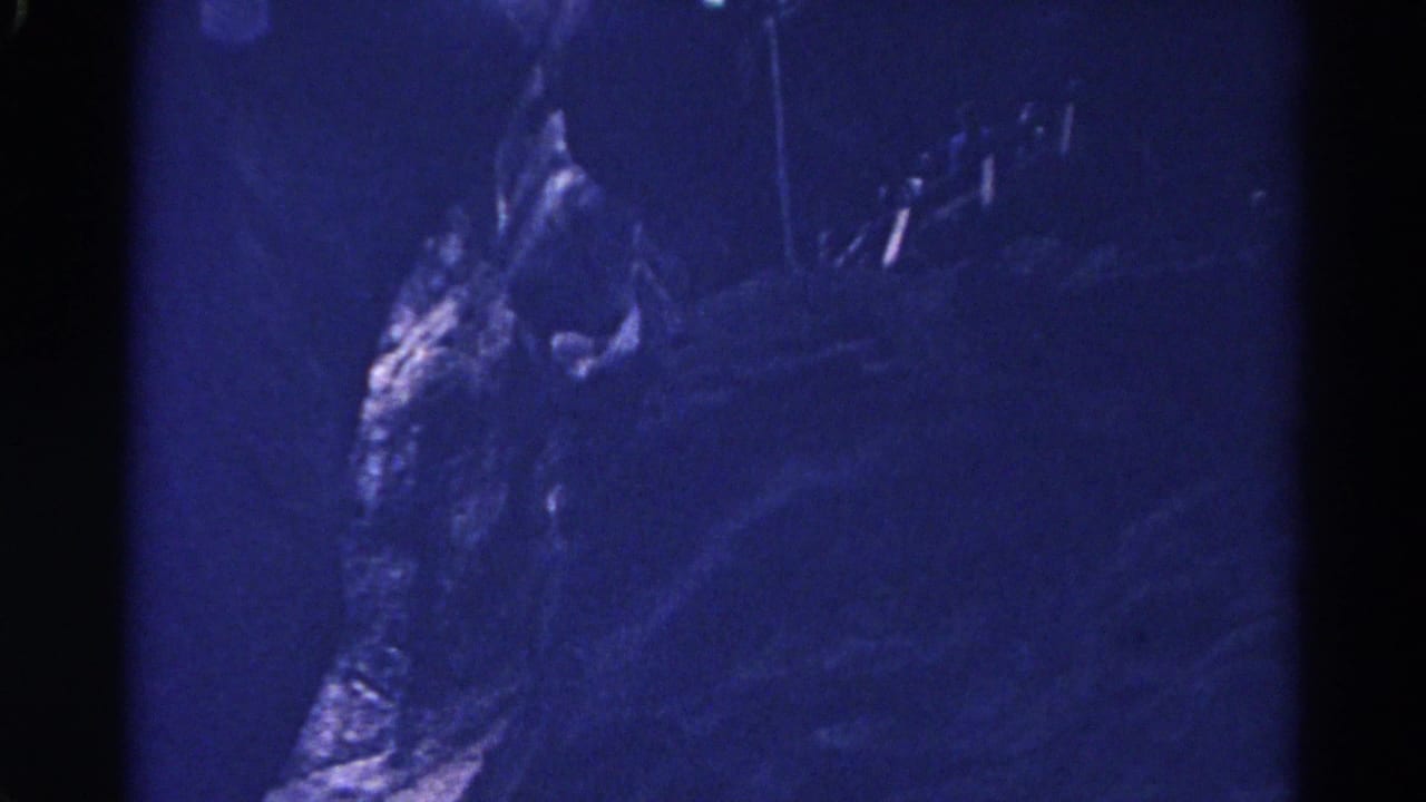 1967 Colorado cave footage shows rough rock surfaces in deep blue shadow, with grain and uneven exposure from the 8mm scan.
