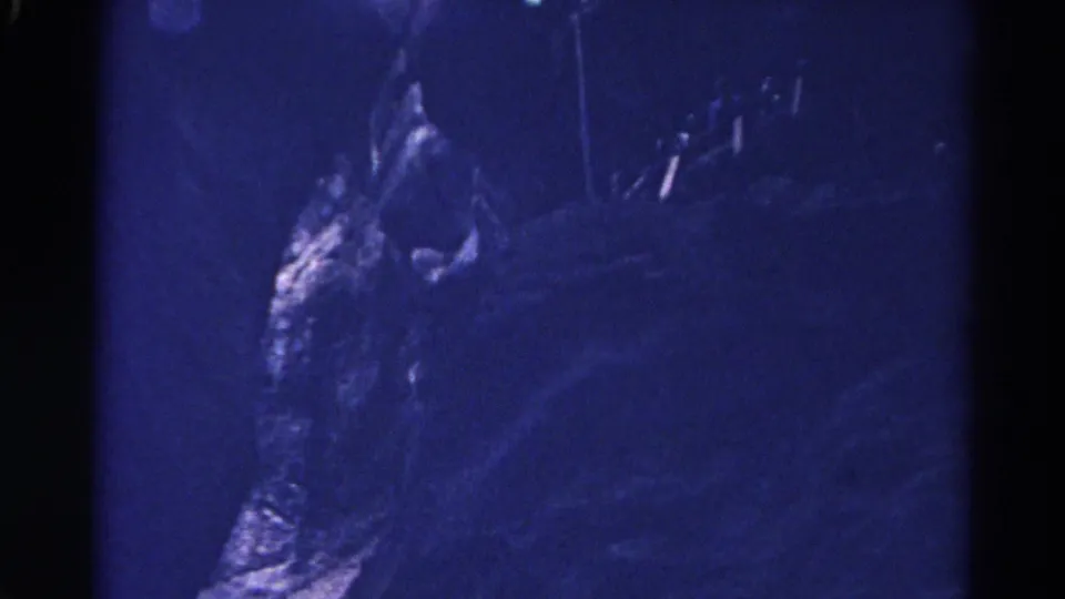 1967 Colorado cave footage shows rough rock surfaces in deep blue shadow, with grain and uneven exposure from the 8mm scan.