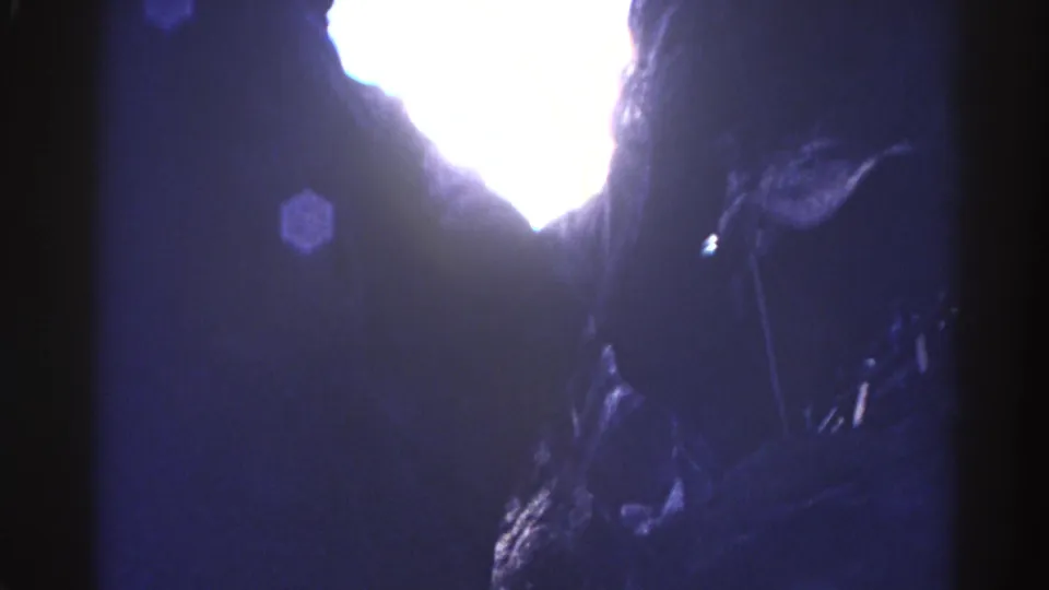 From inside a Colorado cave, the 8mm frame catches a bright opening, dark rock walls, lens flare, and overexposed daylight.