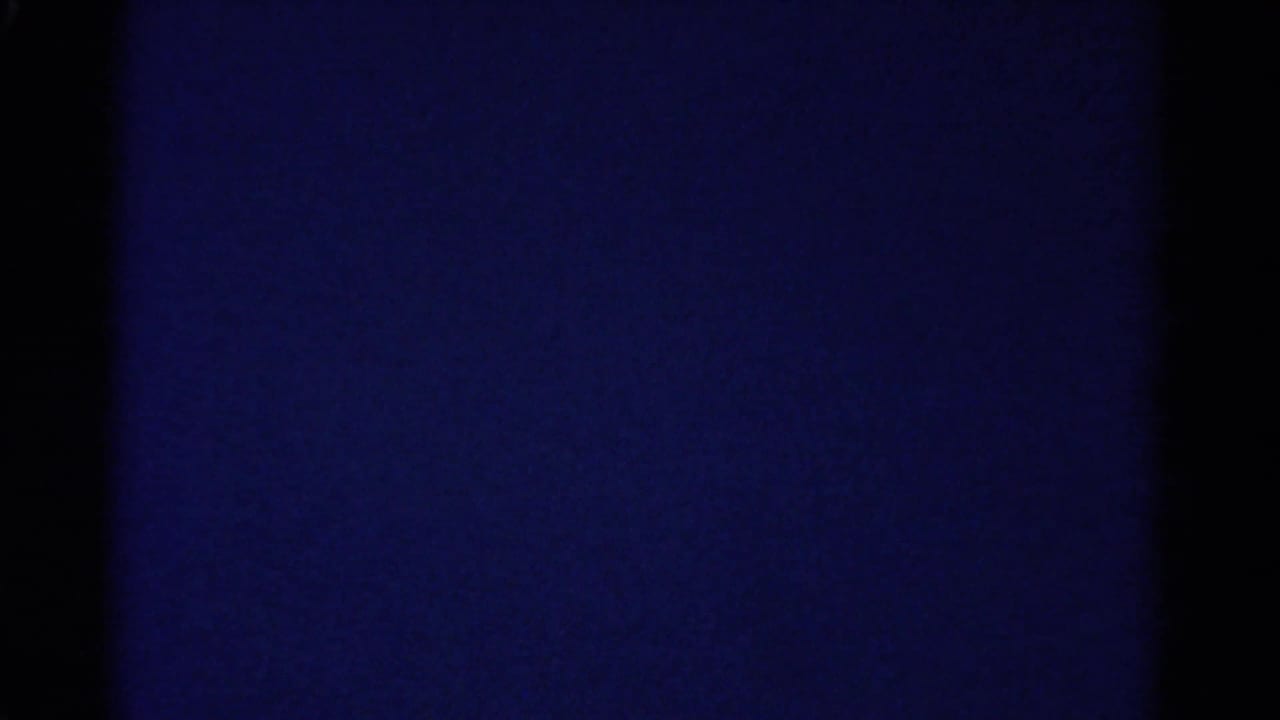 Abstract blue-toned 8mm frame from the 1967 Colorado home-movie clip, with dark film borders and uneven exposure.