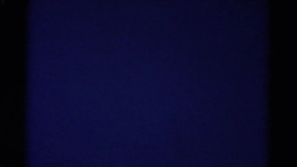 Abstract blue-toned 8mm frame from the 1967 Colorado home-movie clip, with dark film borders and uneven exposure.