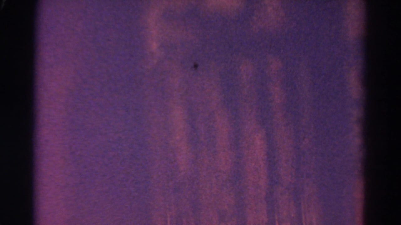 Purple-red abstract 8mm frame with heavy grain, dark edges, and soft exposure shift during the transition.