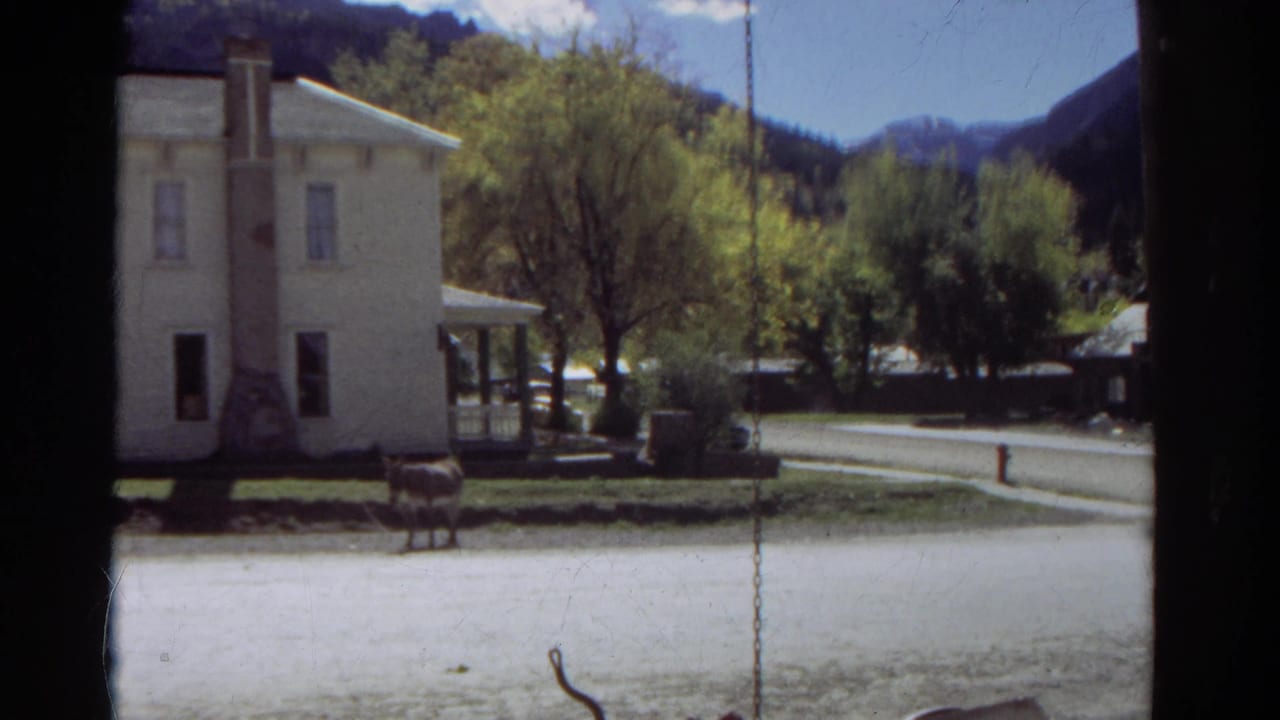 White house, porch, horse, trees, road, and mountain backdrop framed by a dark edge.