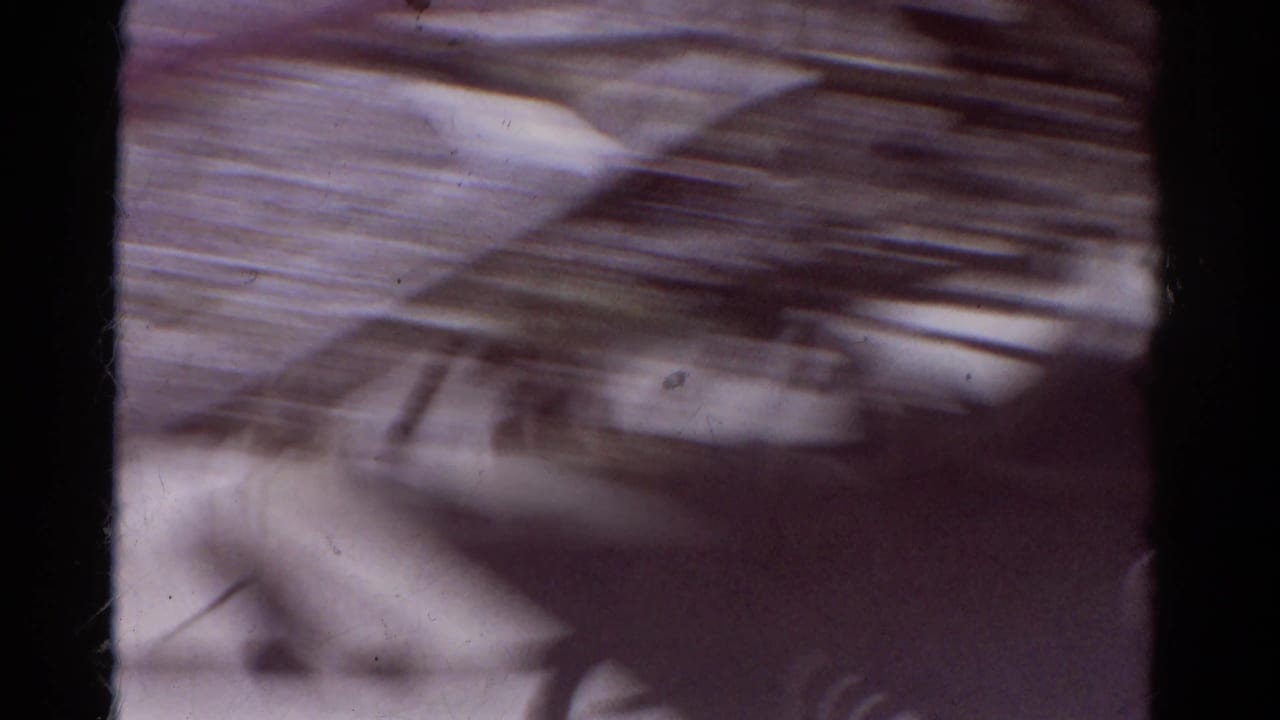Soft, motion-blurred 1967 8mm Colorado frame with dark film edge and an indistinct exterior view before the donkey shot settles.