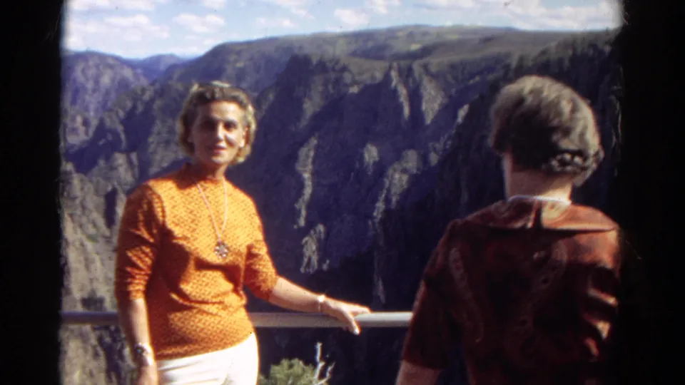 At the Colorado overlook, a second woman enters the foreground as the posed woman stands against the canyon view.