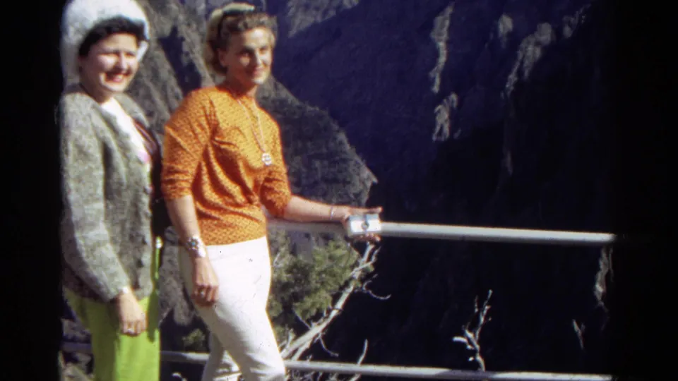 Two women smile for the camera at a 1967 Colorado overlook, framed by a railing and shadowed canyon walls.