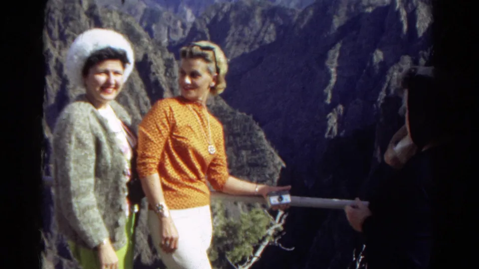 At the end of the 1967 Colorado clip, two women pose beside the overlook railing as a partial figure remains on the right edge.
