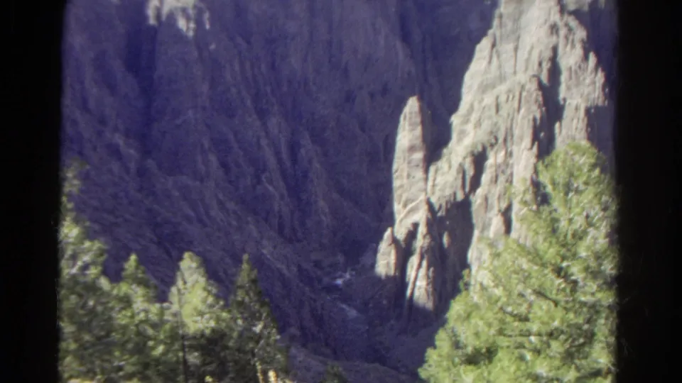 1967 Colorado 8mm scenic view of a steep canyon with light rock spires and evergreens in the foreground.