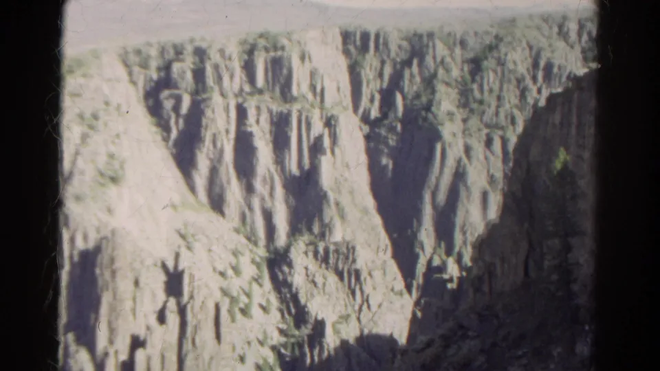 1967 Colorado 8mm frame showing rugged canyon cliffs with vertical rock formations and sparse vegetation.