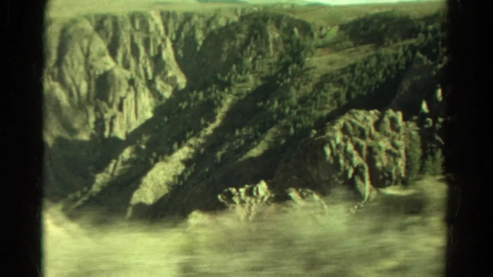 Faded 8mm view of Colorado canyon water, rocky outcrops, and steep shadowed cliffs from a road-trip perspective.