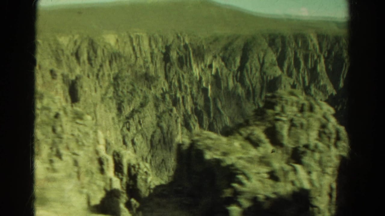 Rocky canyon wall and eroded cliff face seen through dark vertical window edges.