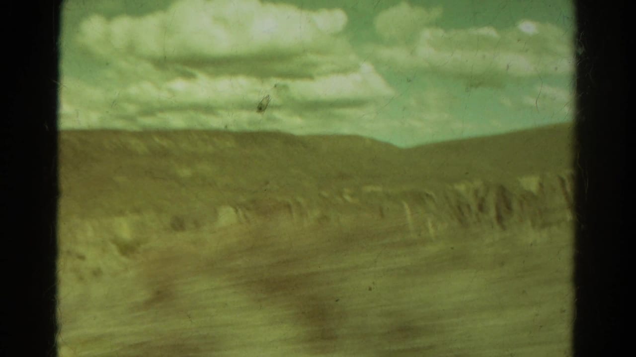 Wide mountain landscape with a pale cloud bank and distant rocky formations.