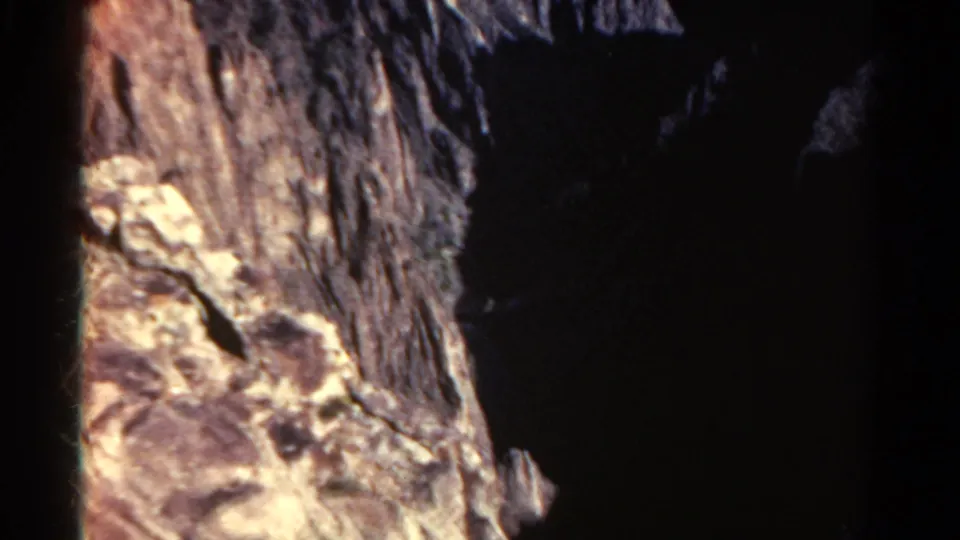 1967 Colorado 8mm frame with pale fractured rocks in the foreground and a dark ravine dropping away beyond.