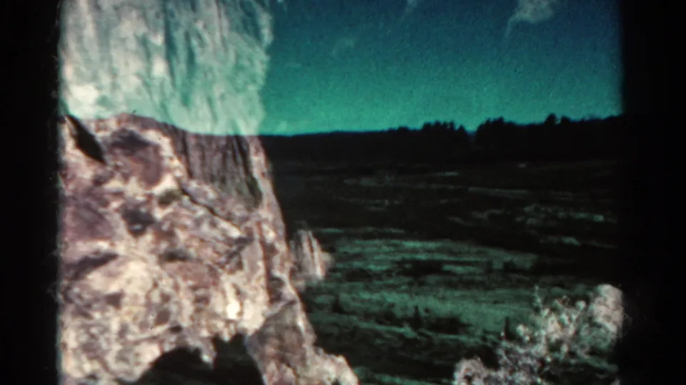 Colorado 1967 home-movie still with soft 8mm texture, a passing foreground object, and rural scenery beyond.