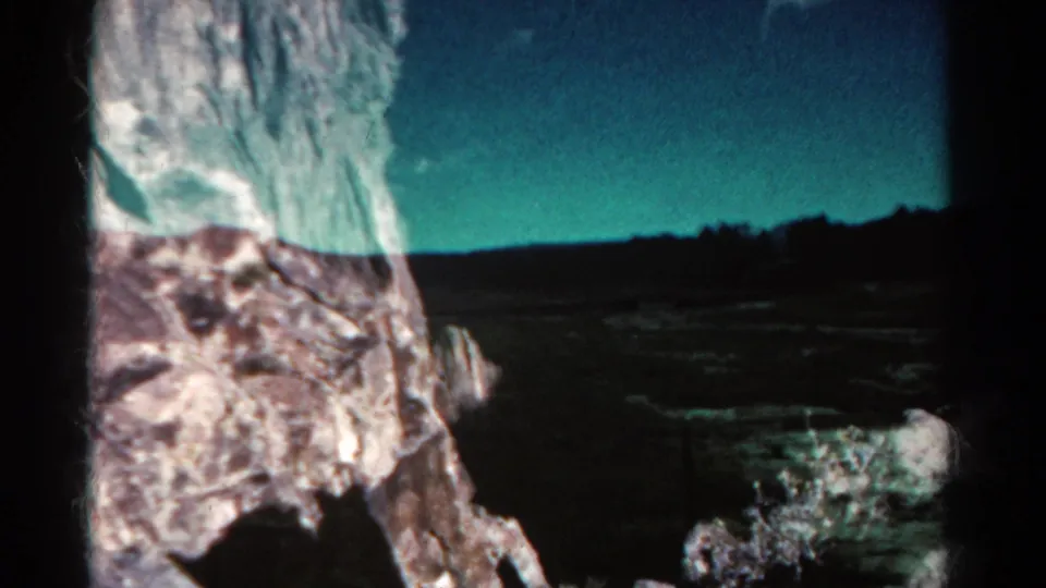 1967 Colorado road-trip frame with open land, distant trees, blue sky, and a pale foreground form near the vehicle window.