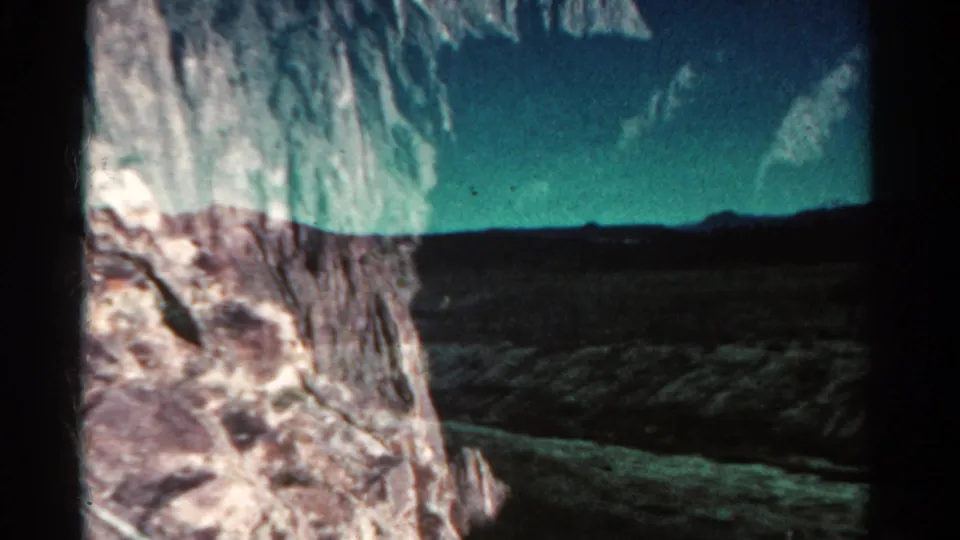 1967 Colorado 8mm view of a pale rock formation with scrubby ground and a low horizon under shifted color.