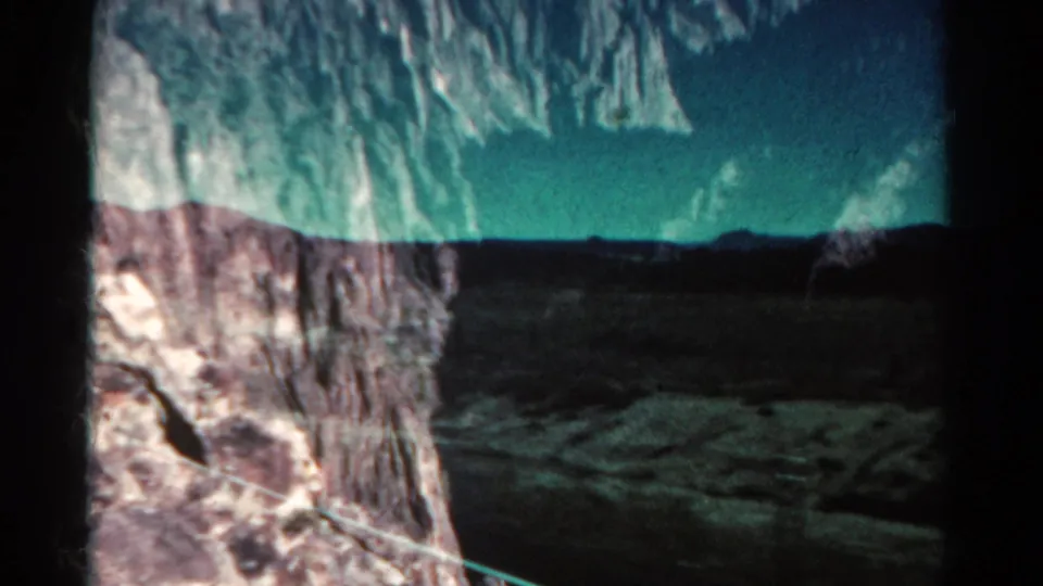 1967 Colorado travel frame looking from a rock outcrop across open land toward a distant mountain range.