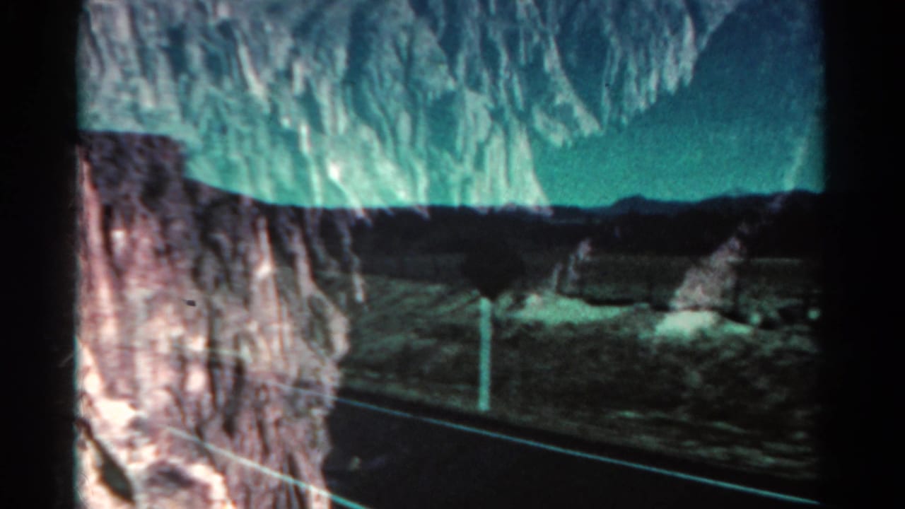 Mountain road and rocky canyon landscape seen through reflective glass.