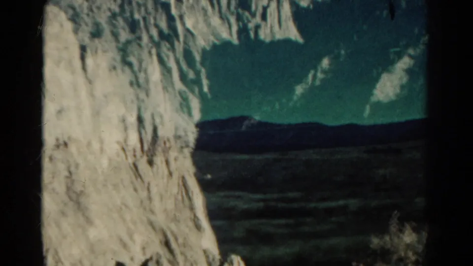 Colorado mountain landscape framed by a pale rock face, with open terrain and distant ridges beyond.