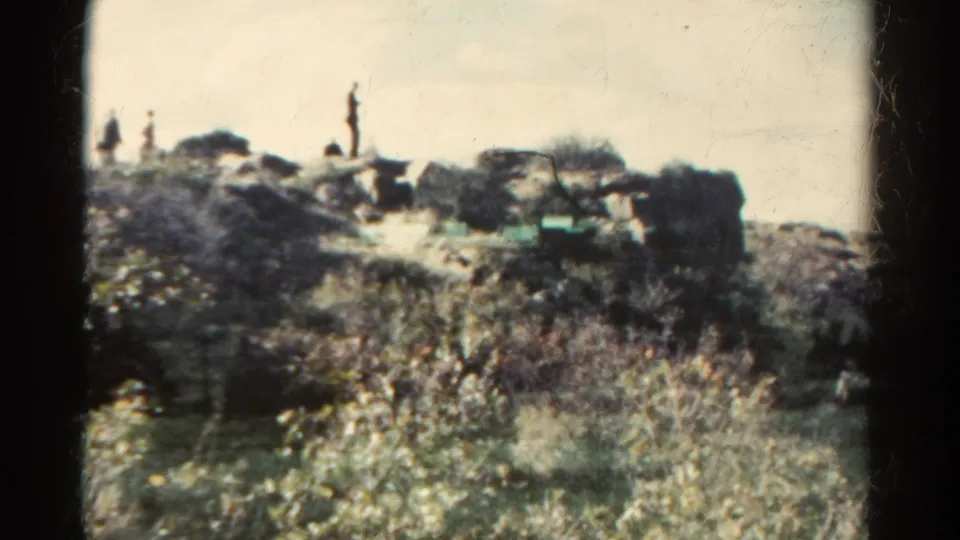 Two or more distant people appear on a rocky Colorado hillside in this 1967 8mm travel shot.