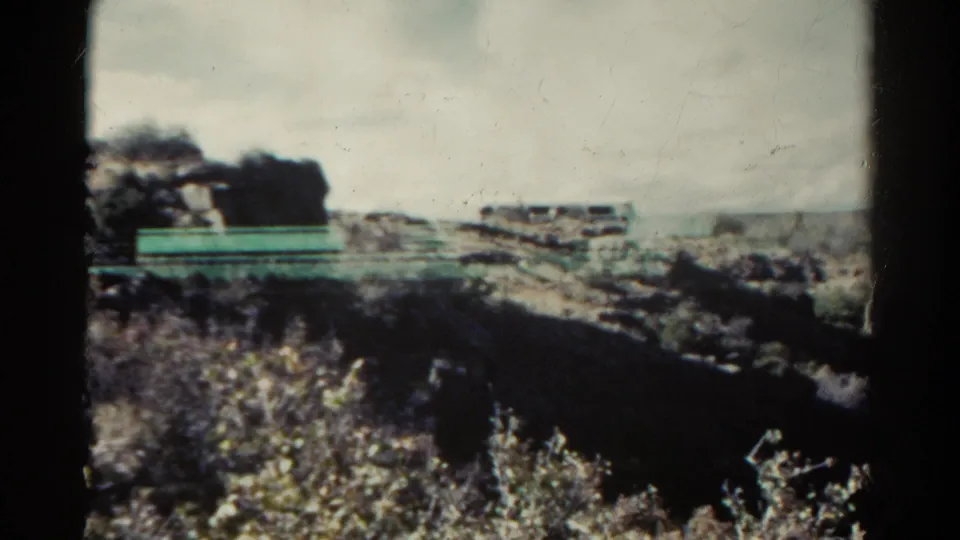 A final 1967 Colorado 8mm frame shows rocky roadside country, pale barriers, scrub, and hazy distant hills.