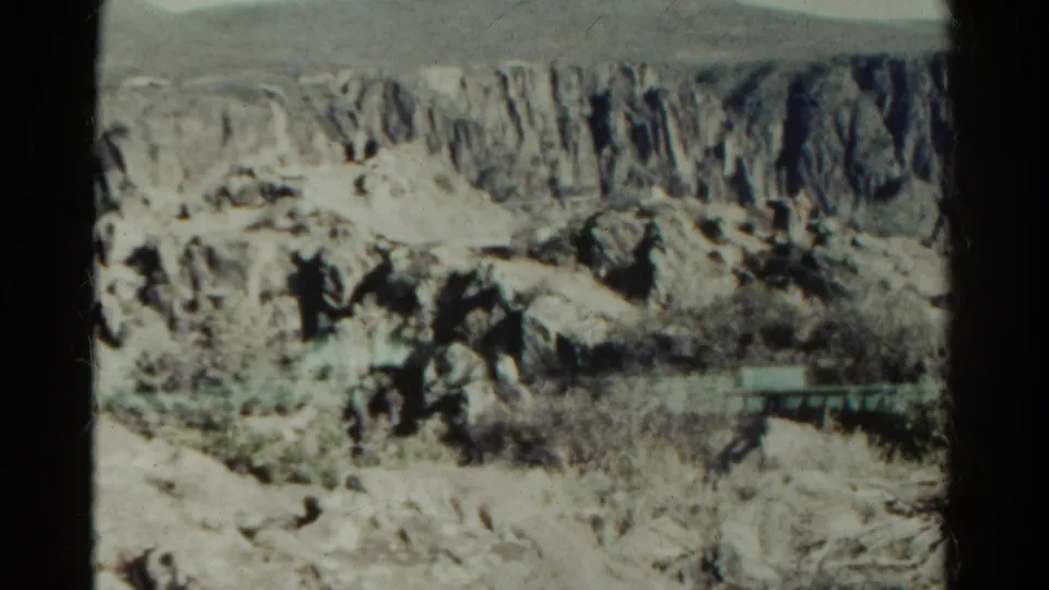 1967 Colorado 8mm frame of canyon terrain with brush and a faint horizontal feature possibly from the double exposure.