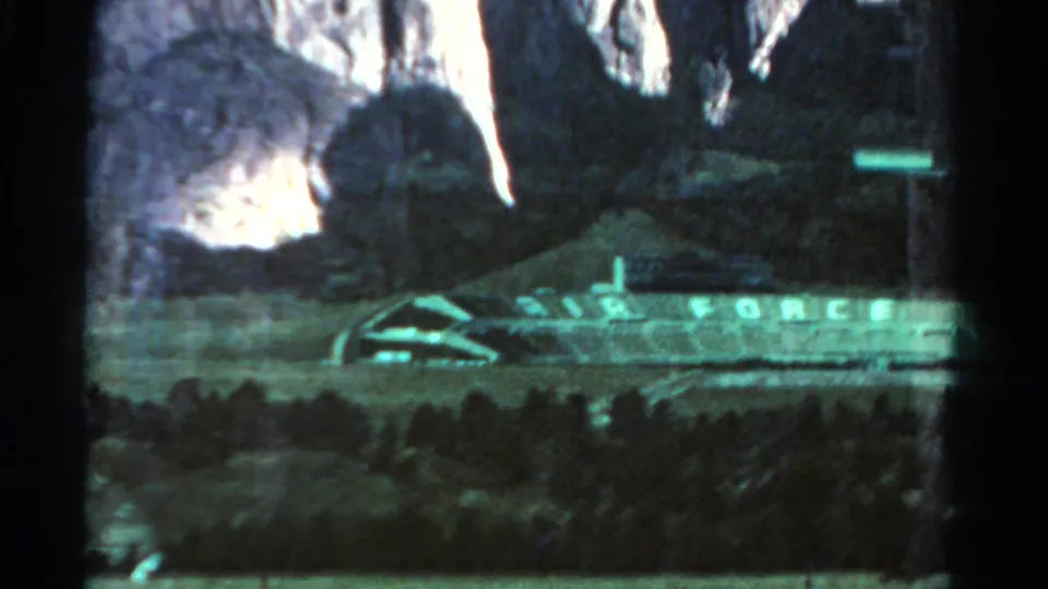 Dark 1967 Colorado 8mm frame with AIR FORCE lettering across a long structure or display, partly obscured by low exposure.