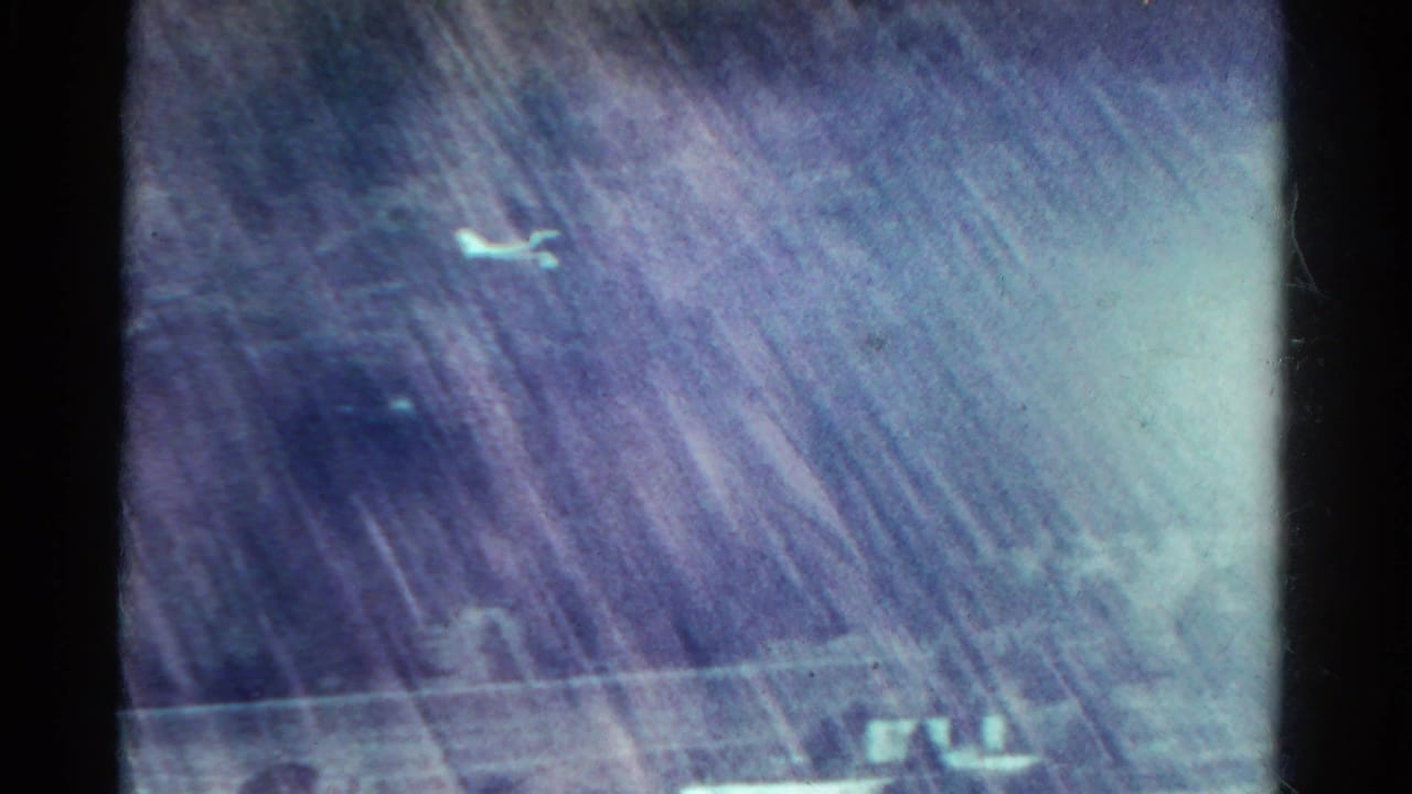 1967 8mm Colorado mountain view with snowy slopes, haze, color fading, and visible film gate edges.