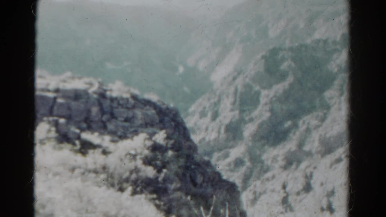 Snow-covered rocky ridge with steep pale mountain slopes behind it.