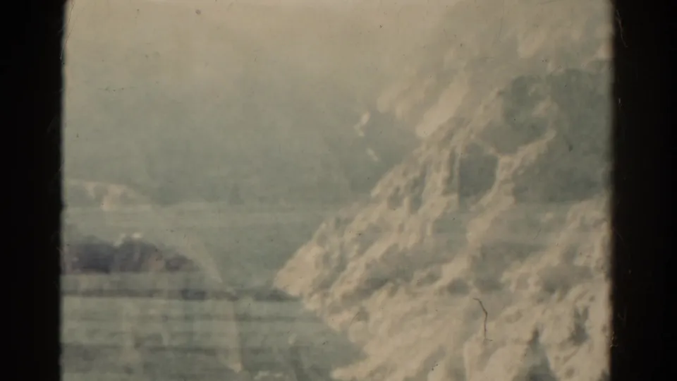 Final 1967 Colorado frame with a rocky hillside, distant plains, muted color, scratches, and dark film-edge framing.