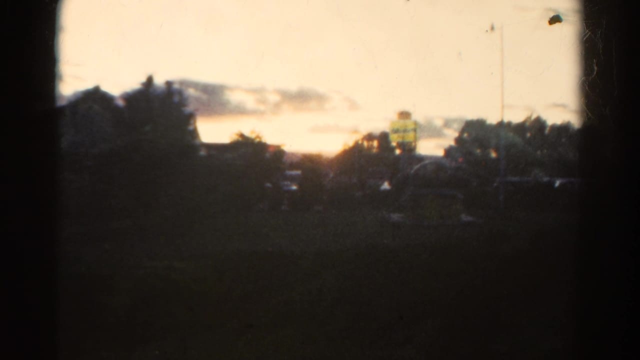 1967 Colorado 8mm frame showing a dim sunset sky beyond silhouetted trees and low clouds.
