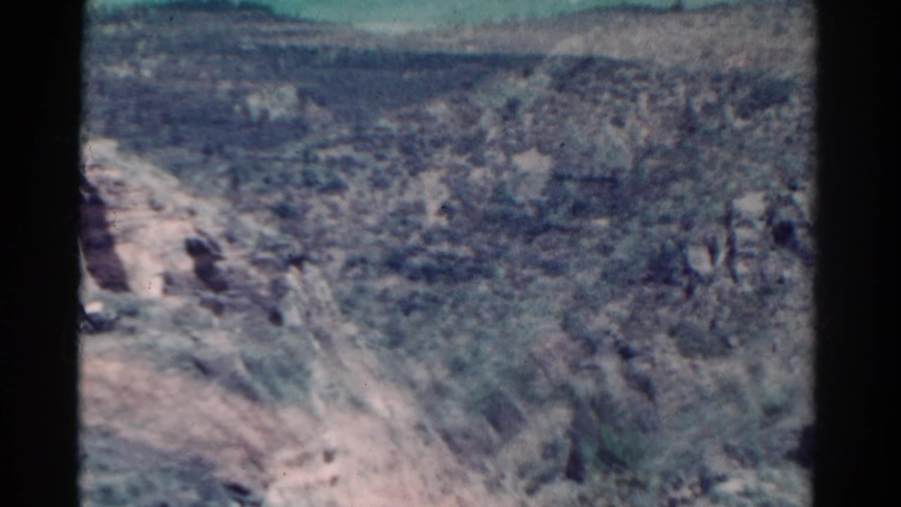 Rocky hillside and scrubland seen from above with dark film border at the side.