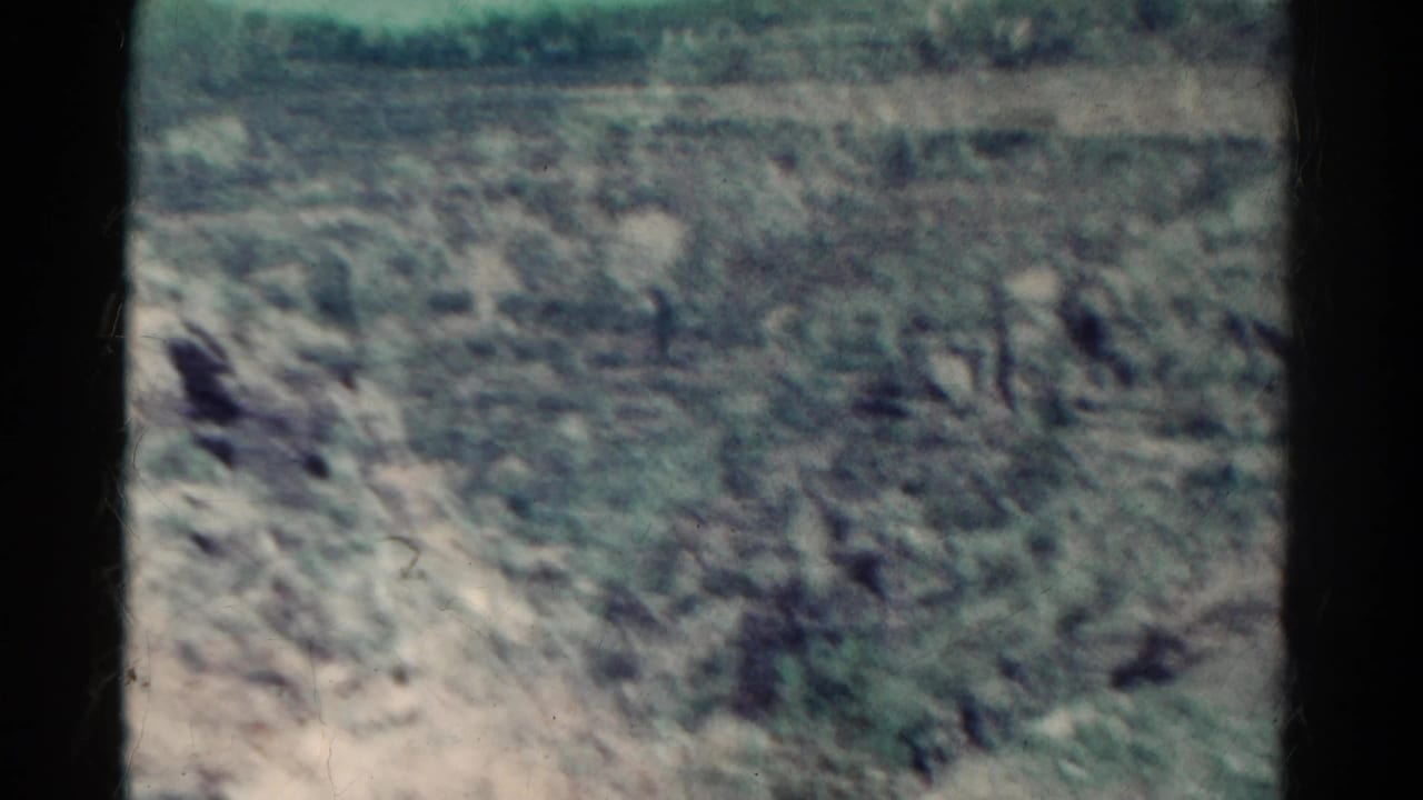 1967 Colorado 8mm frame showing rocky scrubland and a distant hillside, softened by film grain and faded color.