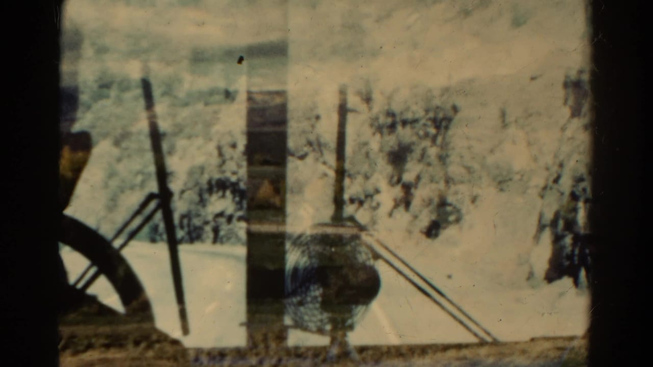 1967 Colorado 8mm frame showing a bus-window view of roadside terrain with pale snow or ground and interior edges in the foreground.