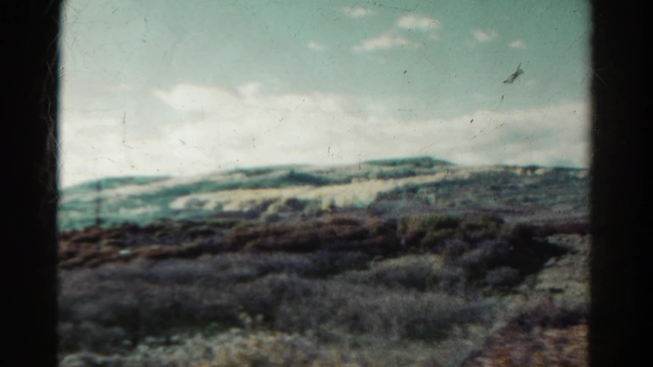 Distant hills under a pale blue sky, with dark scrubland in the foreground.